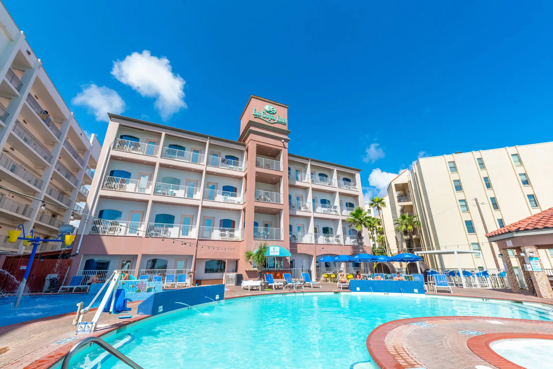 The hotel pool under a bright blue sky, with the La Copa Inn building behind