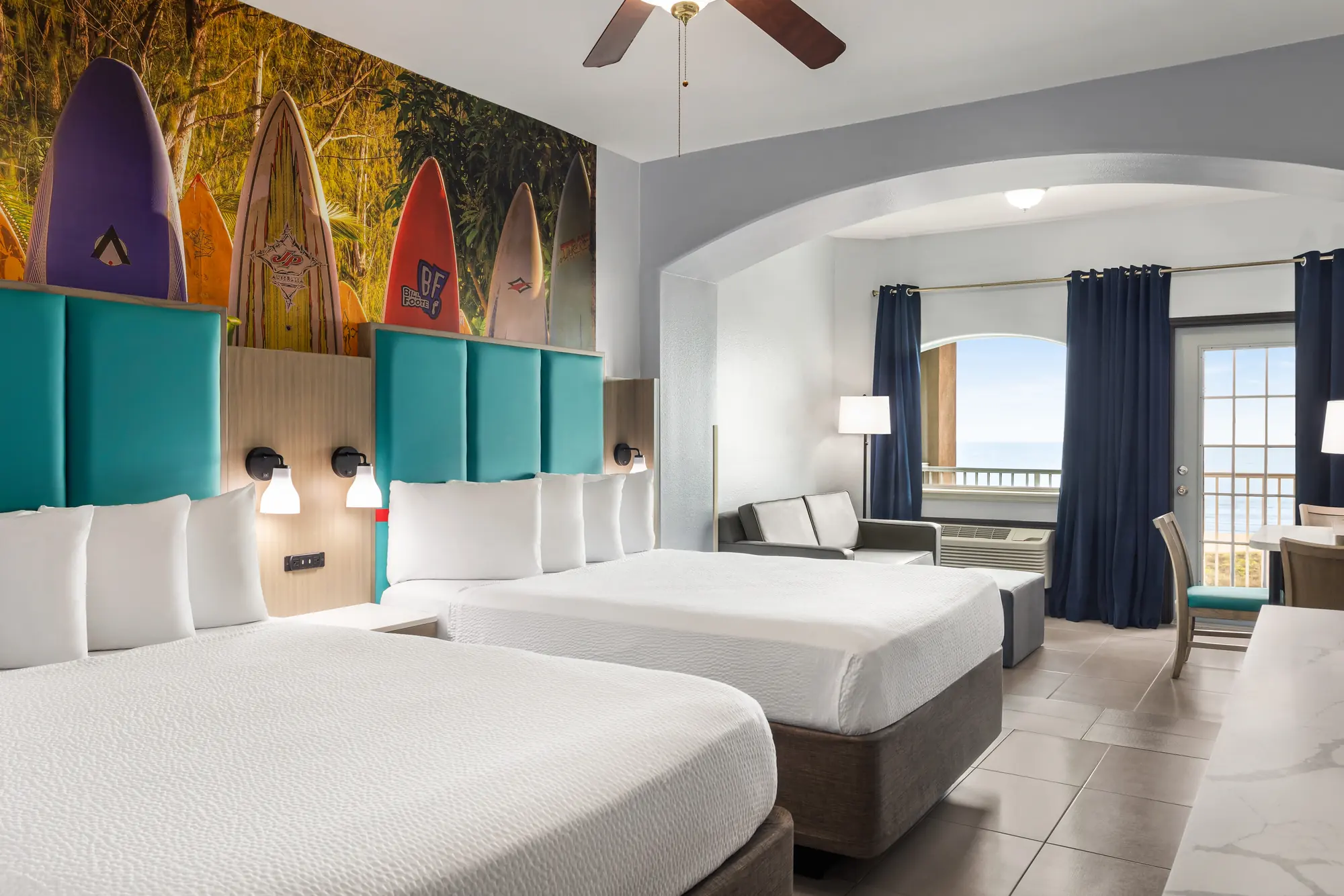 Two Queen Oceanfront room with surfboard mural and teal headboards